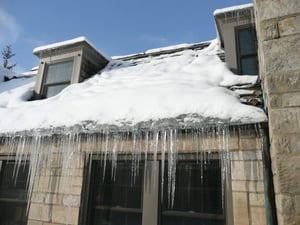 brick home with snow and icicles on the roof